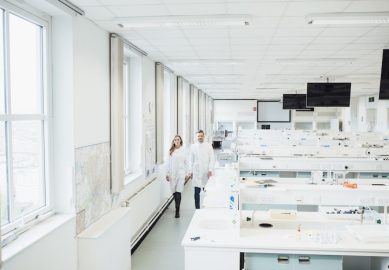 Two scientists walking through a bright laboratory.